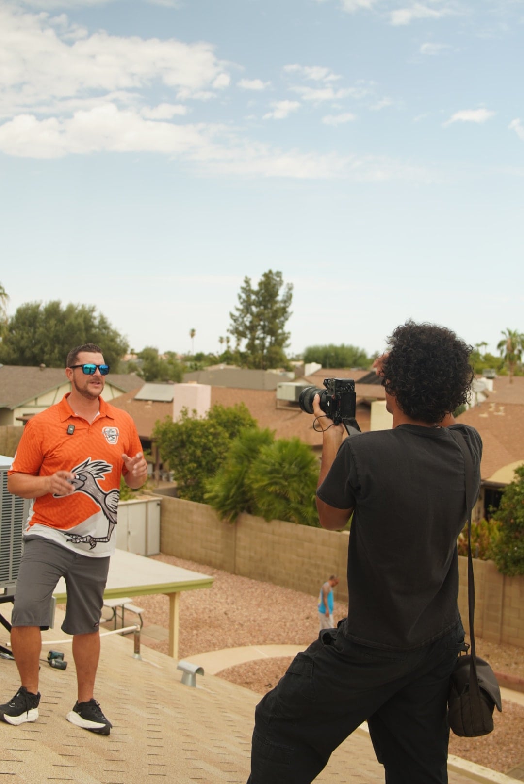 A Stray videographer filming an HVAC contractor beside rooftop equipment